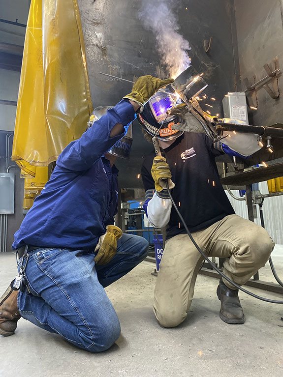 Two people welding.